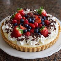 Käsekuchen mit frischen Früchten und Schokoladenspänen